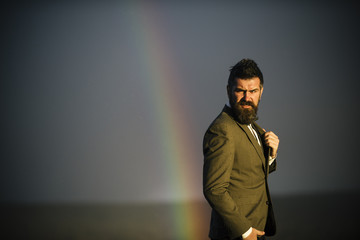 Hipster with beard and mustache on grey sky. Bearded man gay and rainbow. Fashion businessman in...