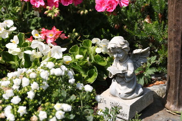 Grabengel zwischen Blumen auf dem Friedhof 