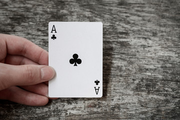 man holding playing card ace of clubs