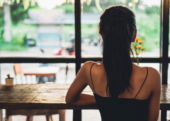 Beautiful woman sitting in coffee shop and looking to outside the window