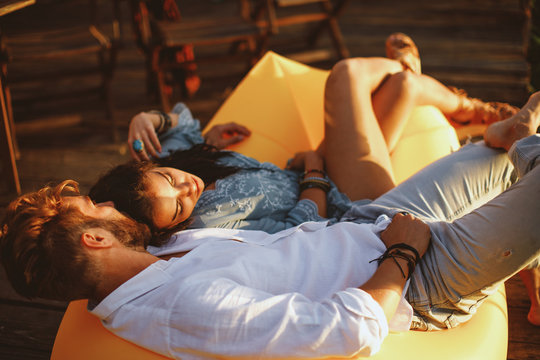 Young couple lying in a lazy bag during the sunset