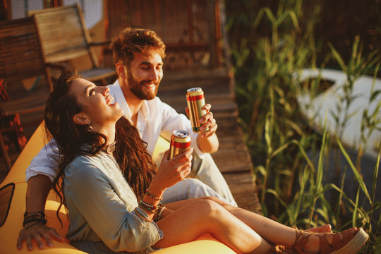 Young happy couple enjoy in beer by the river during the sunset