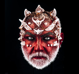 Demon head with evil look. Monster with sharp thorns and warts on face, horror and fantasy concept. Man with white beard and diabolic make-up isolated on black background