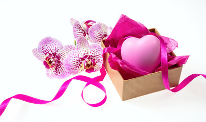 Orchid flowers and small present with a satin ribbon and a pink heart on white background