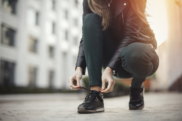 Young attractive girl ties shoelaces.
