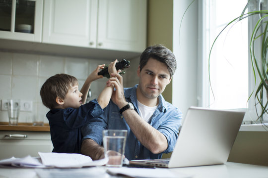 Little son disturbing working freelancer father