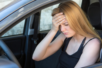 young female driver with headache in a car