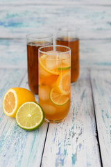 cold, refreshing tea in a glass transparent glass, with ice pieces, lemon and lime slices