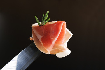 prosciutto jamon on a black background rosemary