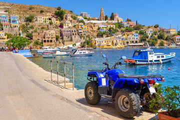 Quad parked on coastal promenade of Symi town. Greece