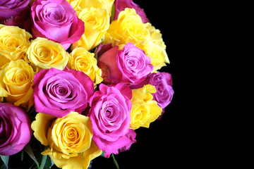 Beautiful round bouquet of pink and uellow roses flowers on left side of the Photo isolated on black background top view closeup