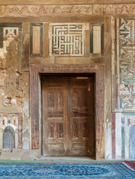 Grunge wooden decorated door  on external old decorated marble wall, El Mardani Mosque, Cairo, Egypt