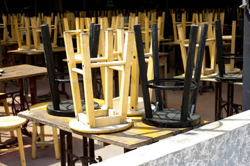 Closed restaurant with old fashioned chairs set upside down on tables at sunny summer day.