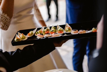Tasty wedding appetizers served by waiters to the guests