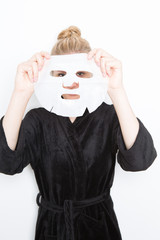 blond woman putting a make-up mask on her face