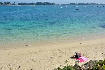 Fototapeta na wymiar Une femme et sa fille sont assises sur une plage de Bretagne