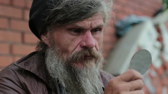 Portrait of a homeless man looking at himself in the mirror