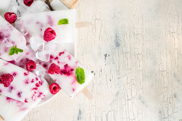 Summer sweet desserts, homemade organic ice cream popsicles from raspberry and yogurt, light beige background copy space