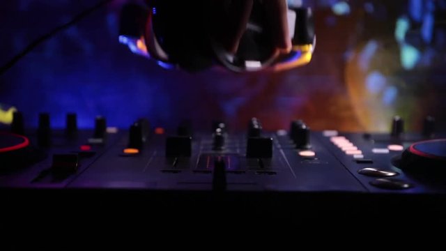 Slider shot. In selective focus of Pro dj controller.The DJ console deejay mixing desk at music party in nightclub with colored disco lights. Close up view