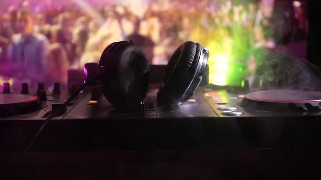 Slider shot. In selective focus of Pro dj controller.The DJ console deejay mixing desk at music party in nightclub with colored disco lights. Close up view
