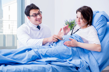 Doctor visiting pregnant in hospital room