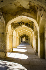 Fototapeta na wymiar Mughal Arches Creating a Pathway along the Outside of a Tomb Appear Golden in the Sunlight at the Qutb Shahi Tombs in Hyderabad, India