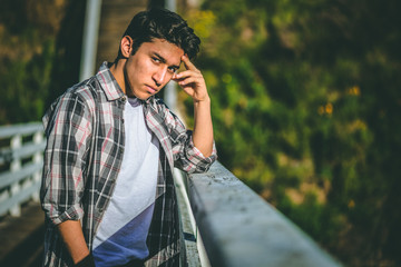 Sad depressed and desperate young male standing on a bridge contemplating suicide hopelessness...