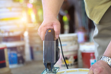 Men are using Electric fretsaw, plastic buckets to make wet bins in the home.