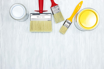 set of various brushes and tins with paint on grey wooden background. flat view
