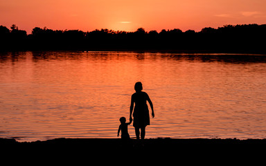 Kids and families are having fun at a lake under sunset