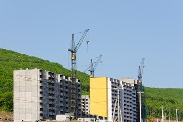 Cranes on a construction site at home against a blue sky