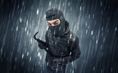 Burglar in action in black clothes with rainy concept. 