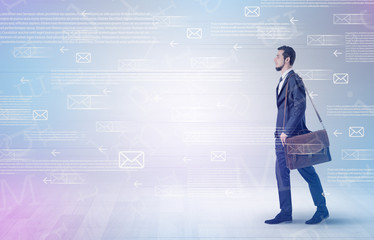 Handsome businessman walking in suit with briefcase on his hand and online communication concept around
