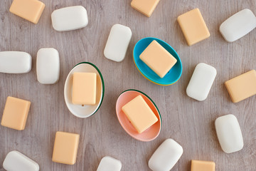 Soap is scattered on a wooden background. View from above. Soap of white and yellow color is scattered on the surface. Soap for body hygiene.