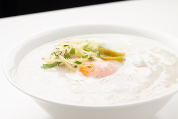 Asian congee with minced pork and egg in white bowl.