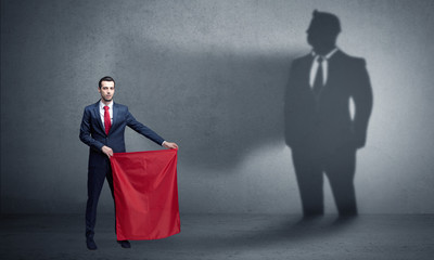 Businessman standing with red cloth on his hand and his shadow on the background
