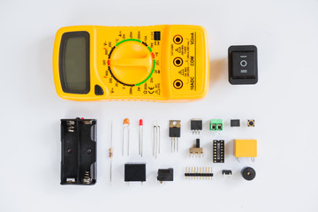 Top view of Multimeter and electronics component such as resistor, ICs, capacitor, switch, relay and connector on white background.