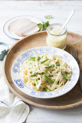 Fresh homemade pasta with asparagus, cheese and cream sauce on wooden tray.