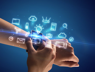 Close up female hand with smartwatch and multimedia symbols around and blue background
