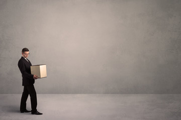 Obraz premium A well dressed young office worker holding an empty paper box with clear concrete wall background concept.