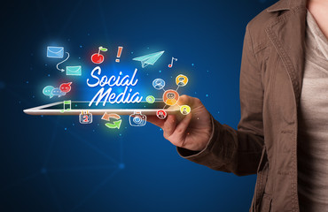 Casual young woman holding tablet with social media icons