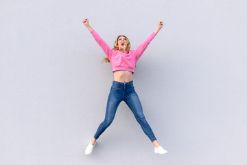 Fototapeta premium Young happy woman in jeans jumping into air