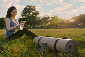 Mat for training with the phone lying on the grass on the background of athlet