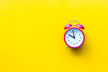 A red alarm clock with ten o'clock on yellow  background with copyspace