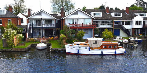 Obraz premium Waterside properties and old fashioned cruiser on the river Bure at Horning.
