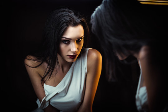 Closeup portrait of seductive young woman looking into mirror