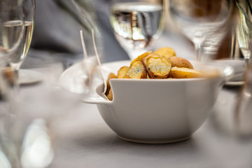Close-up selective focus photography. On the table between the glasses is a white bowl of fried potatoes.