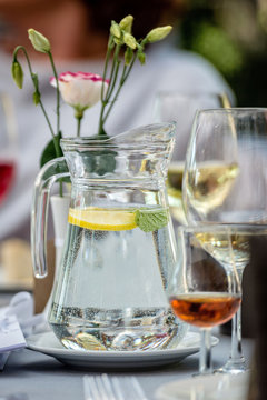 Table laying concept. On the table stands a jug with water and lemon. Glasses in the background.