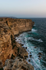 Fototapeta na wymiar Rough seas hitting the cliffs during a colorless sunrise