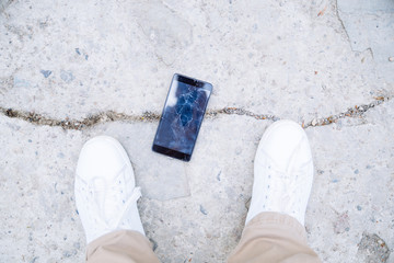 phone with cracked screen on ground. overhead view